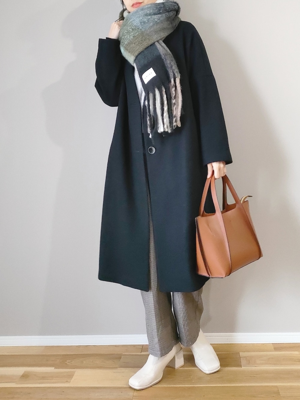 ブラウン系のショルダーバッグ、ブラック系のジャケット/アウター、ホワイト系のブーツを着用したレディースの冬コーディネートの3枚目の写真