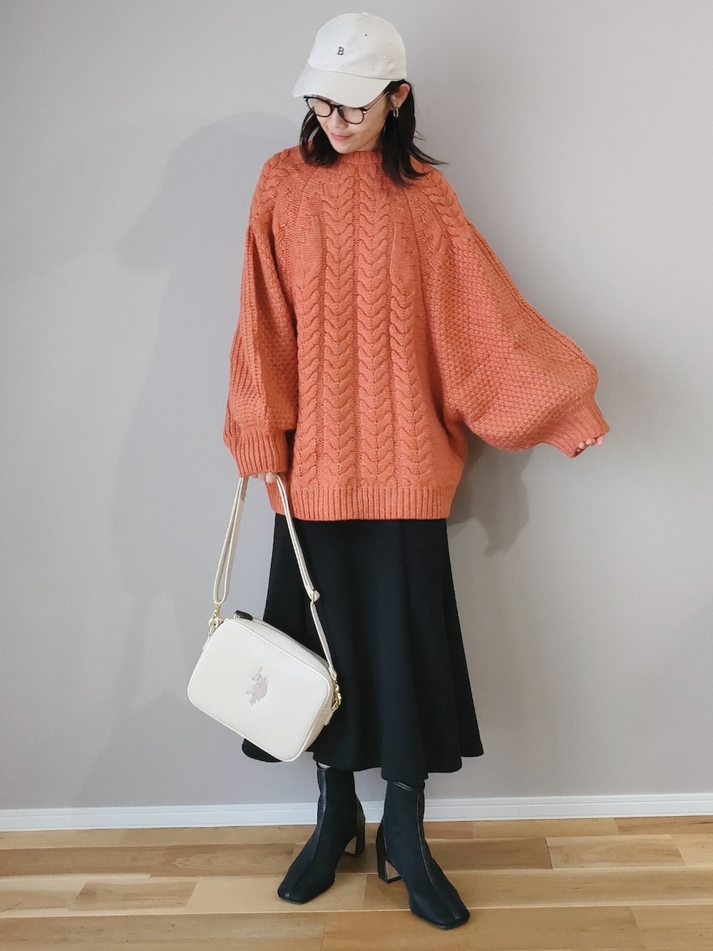 ブラウン系のニット/セーター、ホワイト系のショルダーバッグ、ブラック系のスカートを着用したレディースの冬コーディネートの2枚目の写真