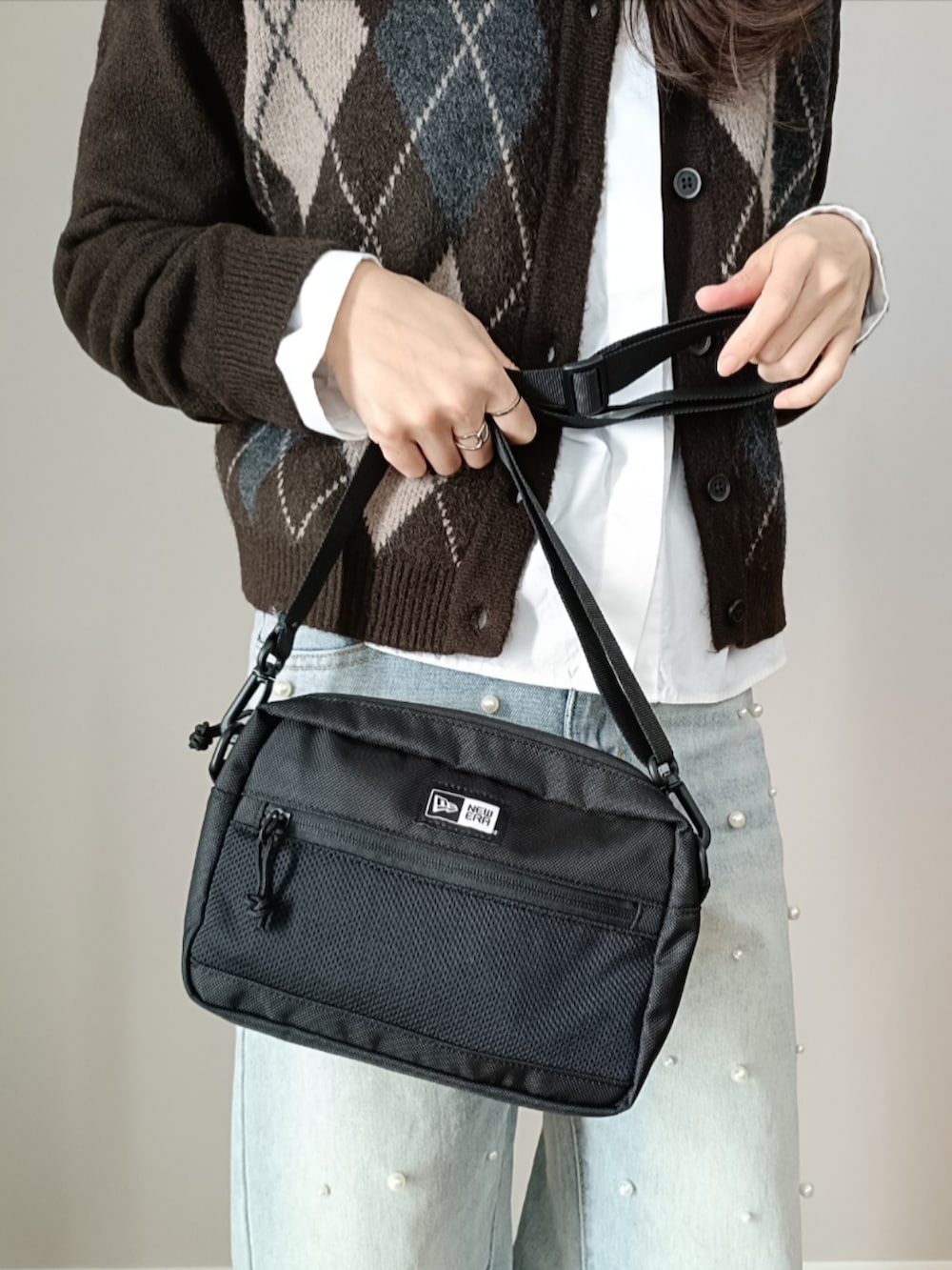 ブルー系のデニムパンツ、ブラック系のショルダーバッグ、ブラウン系のカーディガン/ボレロを着用したレディースの冬コーディネートの3枚目の写真