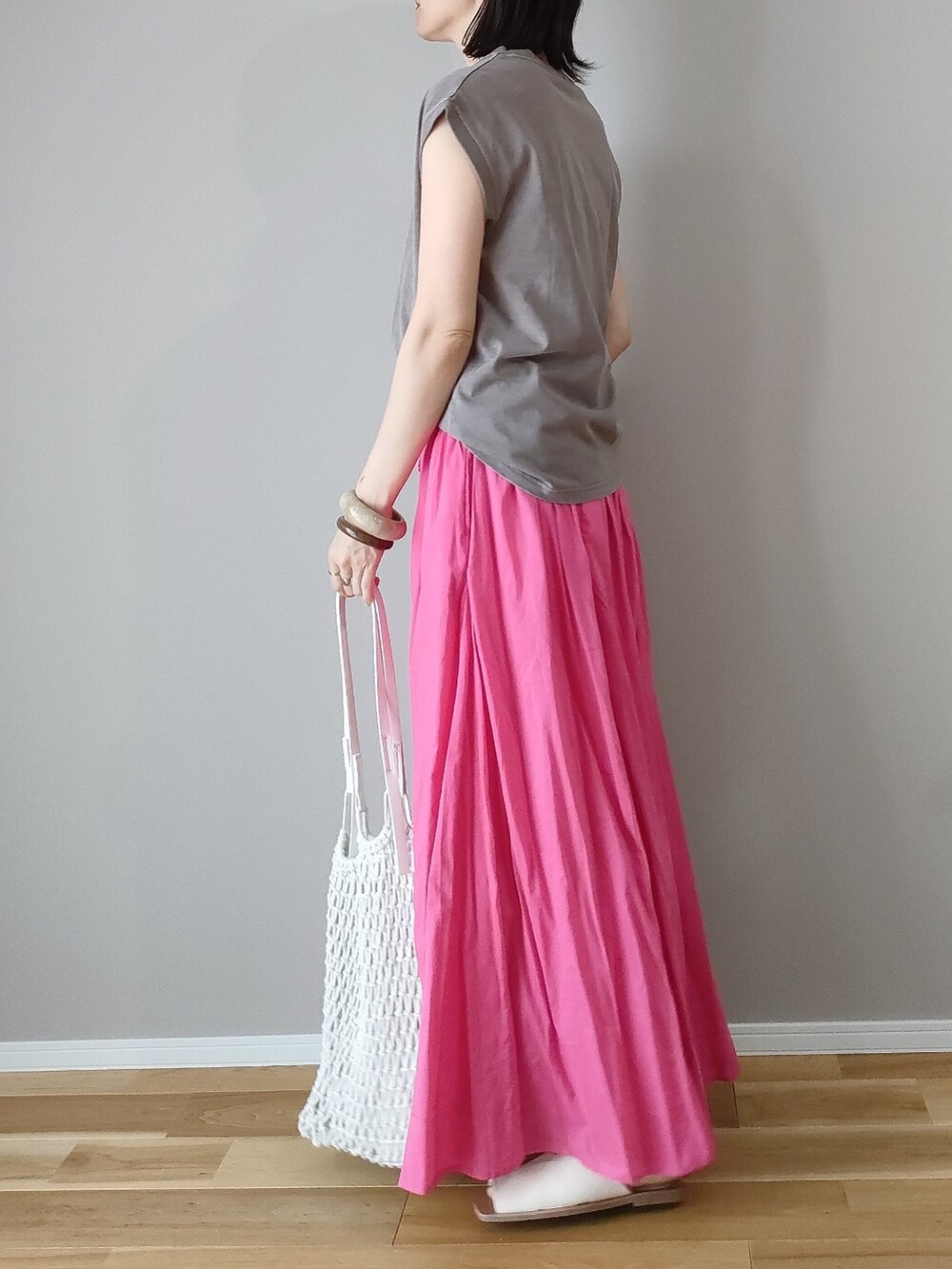 ピンク系のスカート、ブラウン系のTシャツ/カットソー、ホワイト系のトートバッグを着用したレディースの夏コーディネートの2枚目の写真