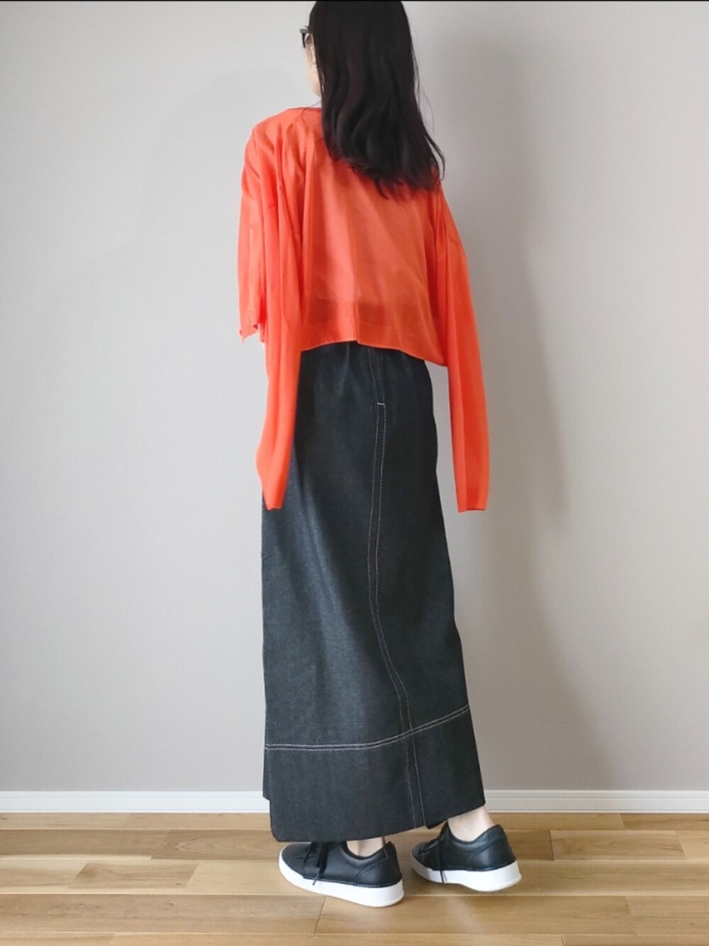 ベージュ系のTシャツ/カットソー、ブラック系のスカート、オレンジ系のカーディガン/ボレロを着用したレディースの春コーディネートの4枚目の写真