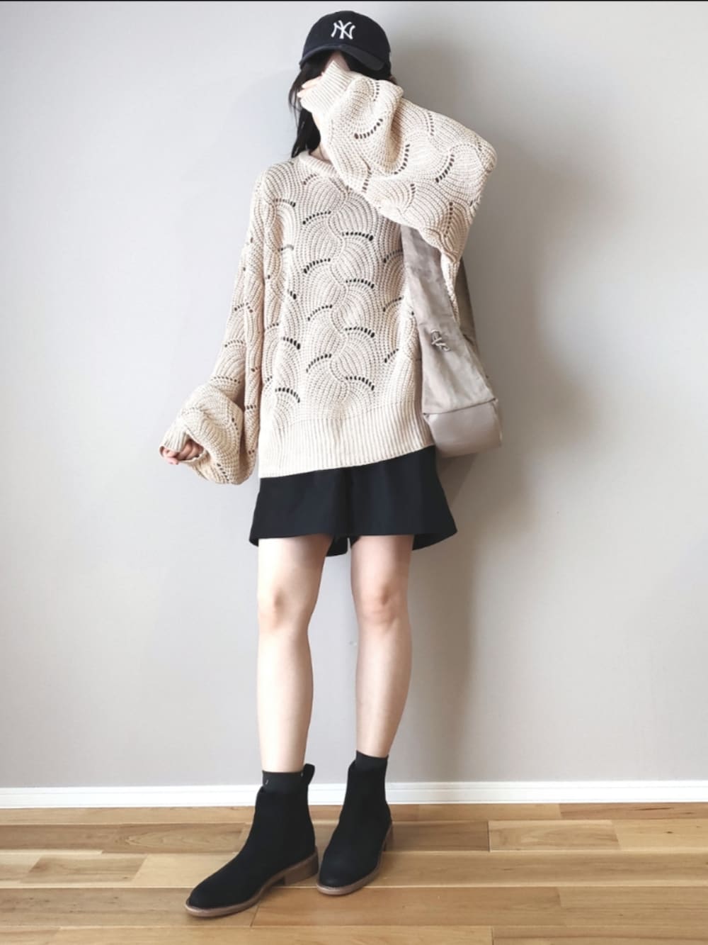 ホワイト系のニット/セーター、ベージュ系のハンドバッグ、ブラック系のブーツを着用したレディースの秋コーディネートの4枚目の写真