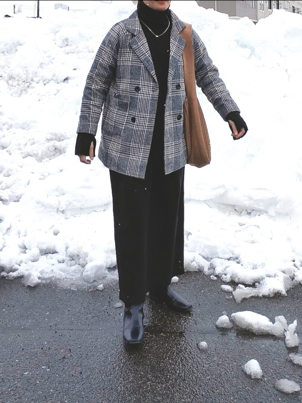 グレー系のチェスターコート、ブラウン系のトートバッグ、ブラック系のワンピースを着用したレディースの冬コーディネートの4枚目の写真