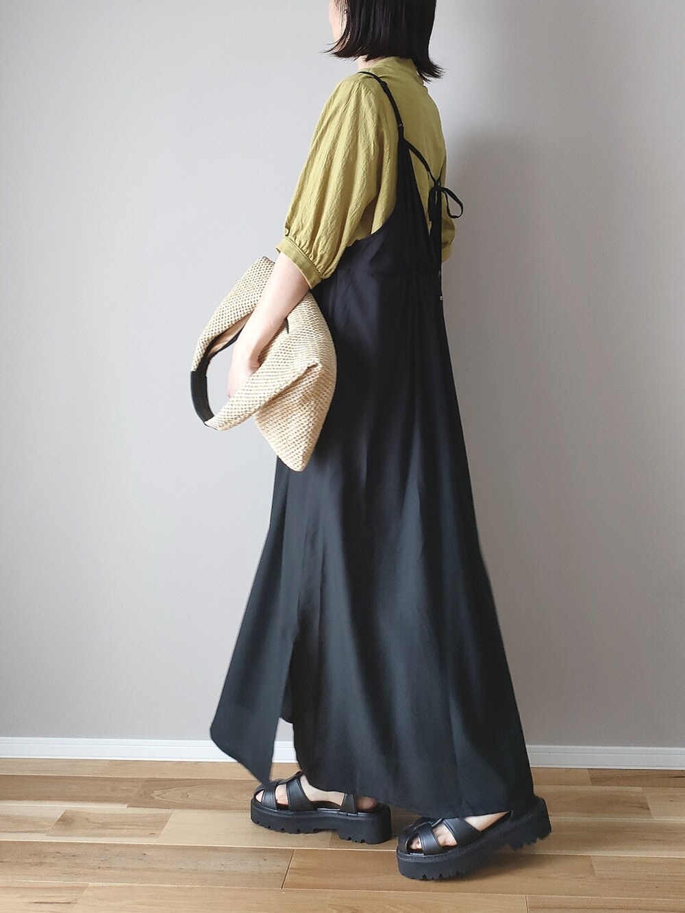 ブラック系のワンピース、ブラック系のサンダル、ベージュ系のショルダーバッグを着用したレディースの春コーディネートの3枚目の写真