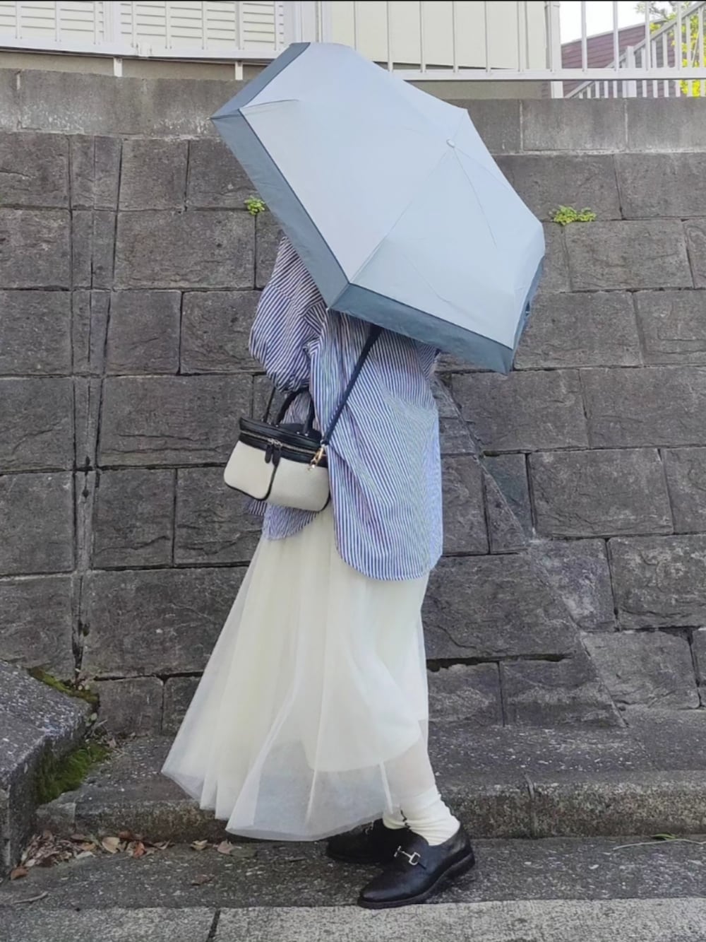 ブルー系のシャツ/ブラウス、ホワイト系のスカート、ブラック系のローファーを着用したレディースの春コーディネートの2枚目の写真