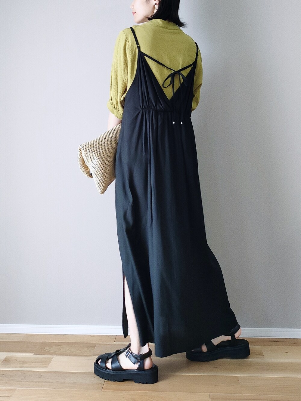 ブラック系のワンピース、ブラック系のサンダル、ベージュ系のショルダーバッグを着用したレディースの春コーディネートの2枚目の写真