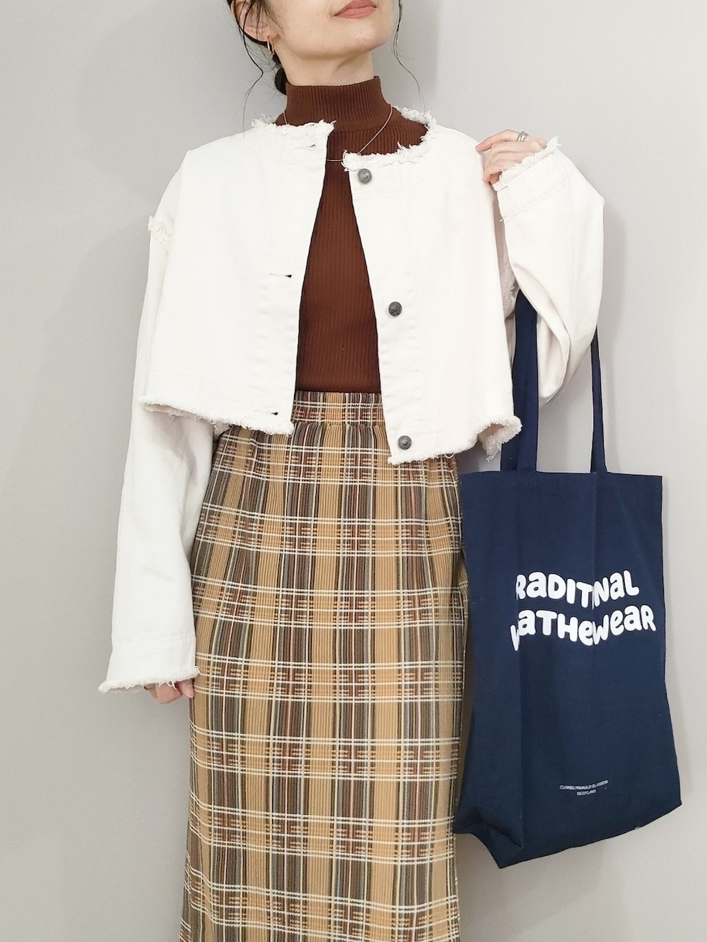 ホワイト系のデニムジャケット、イエロー系のスカート、ブルー系のトートバッグを着用したレディースの冬コーディネートの2枚目の写真