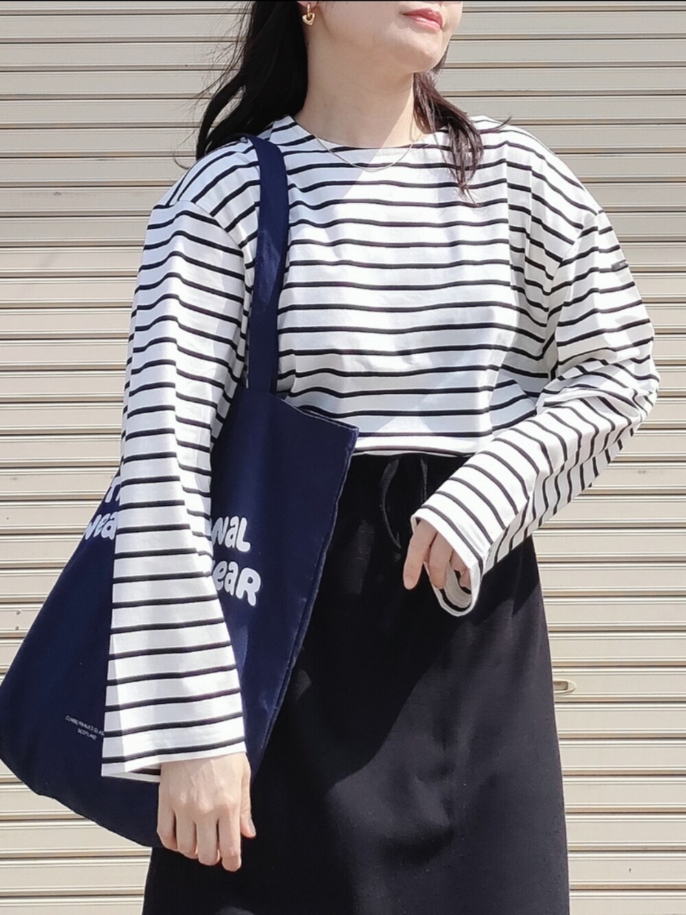 ホワイト系のTシャツ/カットソー、ブラック系のスカート、ブルー系のトートバッグを着用したレディースの春コーディネートの3枚目の写真