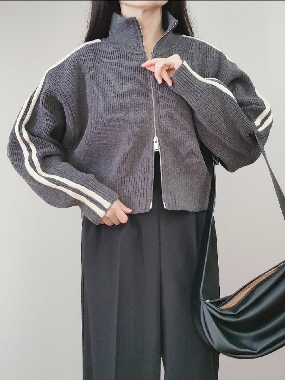 グレー系のニット/セーター、ブラック系のサロペット/オーバーオール、ホワイト系のスニーカーを着用したレディースの冬コーディネートの3枚目の写真