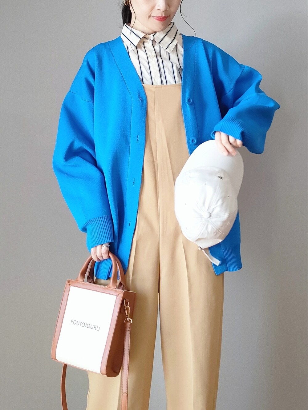 ブルー系のカーディガン/ボレロ、ベージュ系のつなぎ/オールインワン、ホワイト系のブーツを着用したレディースの春コーディネートの2枚目の写真