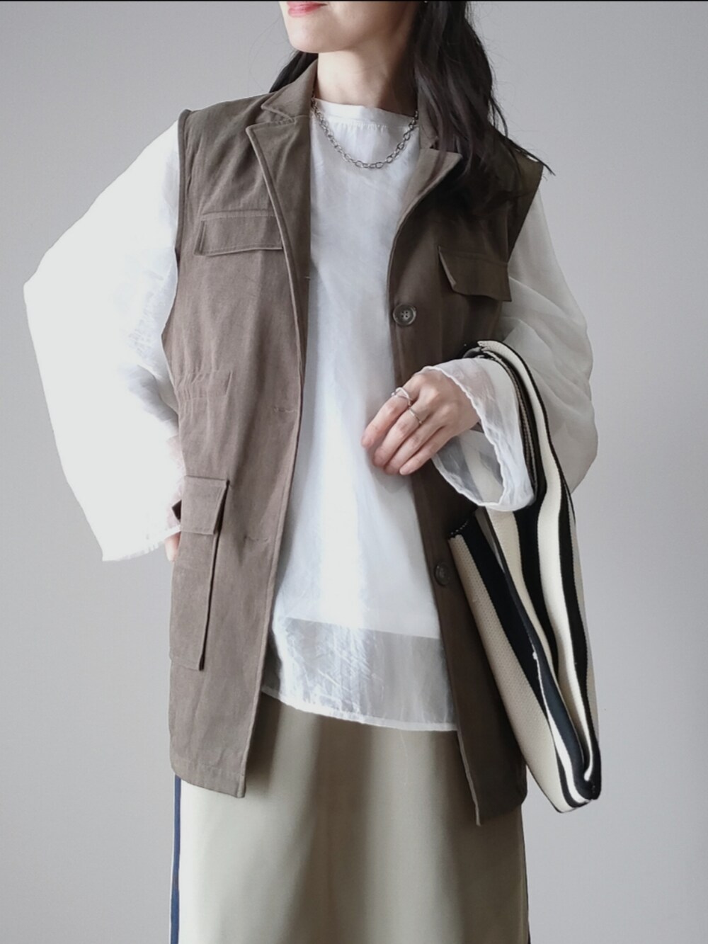 ホワイト系のシャツ/ブラウス、グリーン系のベスト、ブルー系のスカートを着用したレディースの秋コーディネートの2枚目の写真