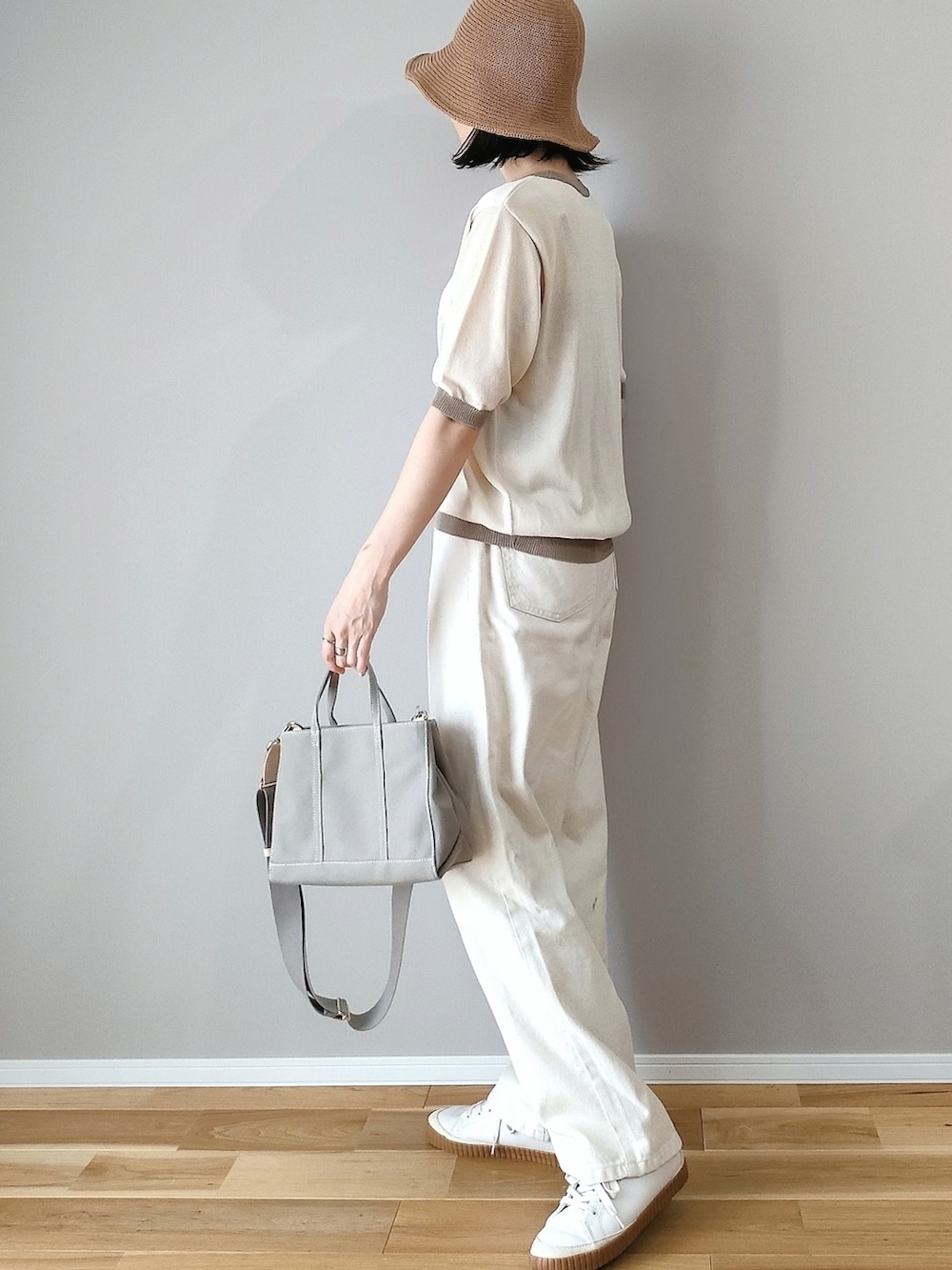 ベージュ系のニット/セーター、グレー系のハンドバッグ、ホワイト系のデニムパンツを着用したレディースの春コーディネートの3枚目の写真