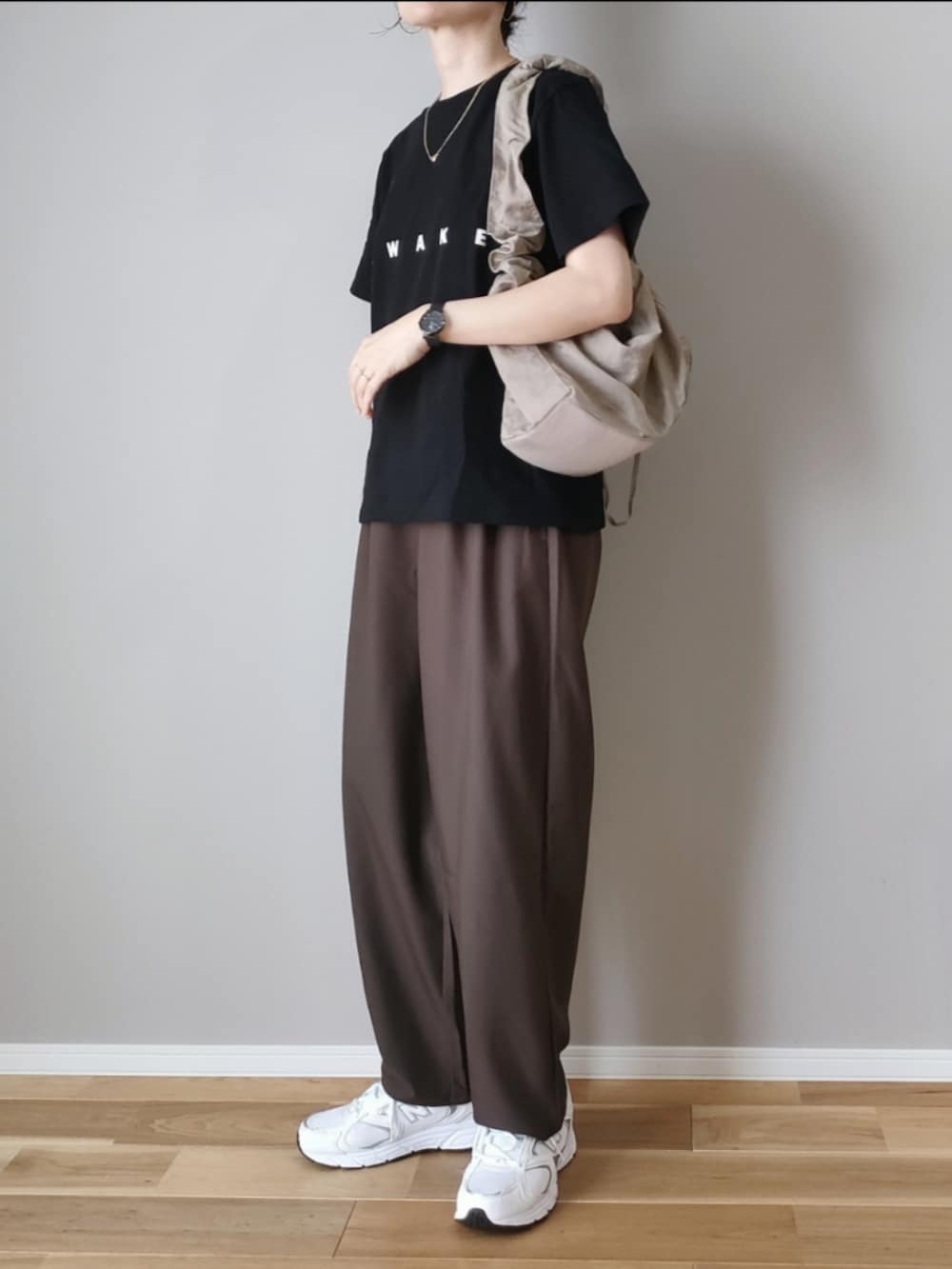 ブラウン系のスラックス、ブラック系のTシャツ/カットソー、ベージュ系のハンドバッグを着用したレディースの秋コーディネートの3枚目の写真