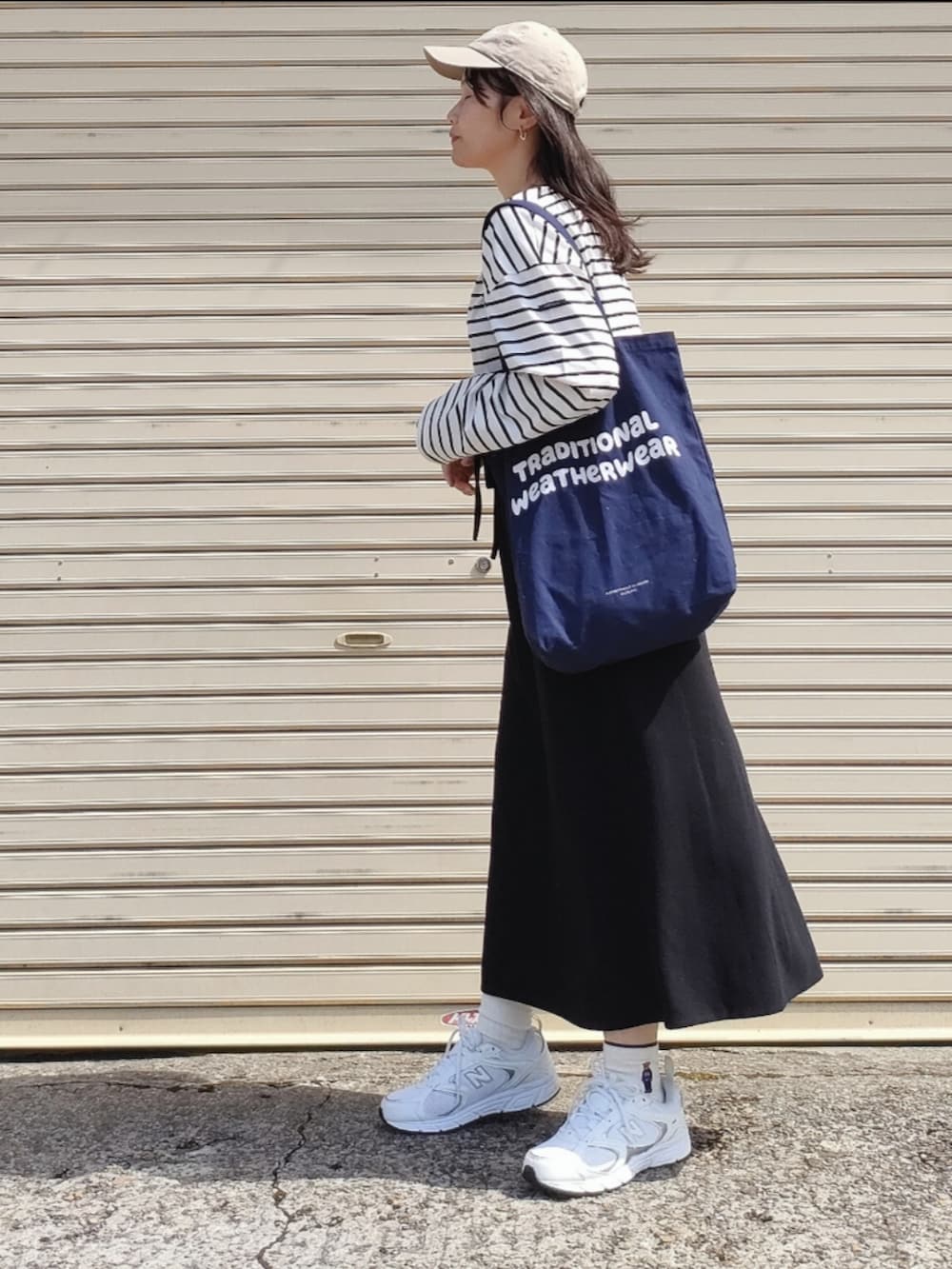 ホワイト系のTシャツ/カットソー、ブラック系のスカート、ブルー系のトートバッグを着用したレディースの春コーディネートの4枚目の写真