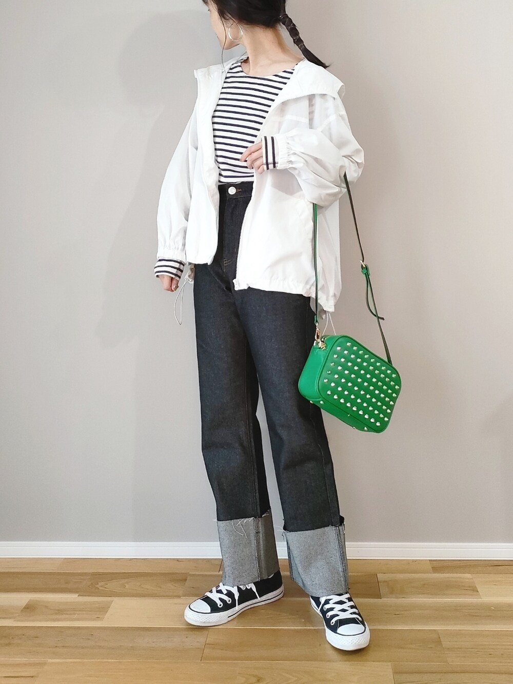グリーン系のショルダーバッグ、ホワイト系のマウンテンパーカー、ブラック系のデニムパンツを着用したレディースの春コーディネートの3枚目の写真