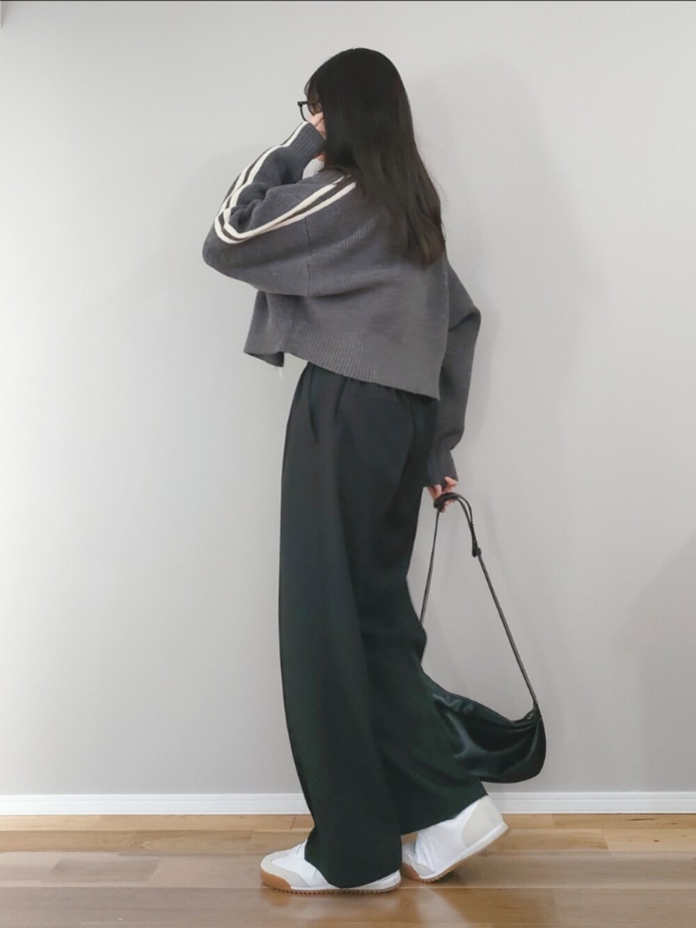 グレー系のニット/セーター、ブラック系のサロペット/オーバーオール、ホワイト系のスニーカーを着用したレディースの冬コーディネートの2枚目の写真