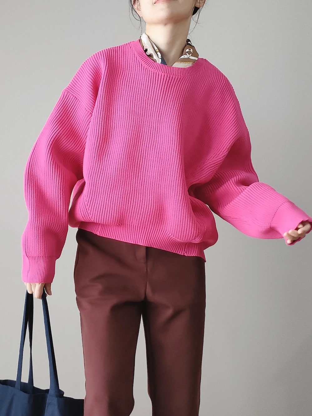 ピンク系のニット/セーター、ブラウン系のスラックス、ブルー系のトートバッグを着用したレディースの秋コーディネートの2枚目の写真