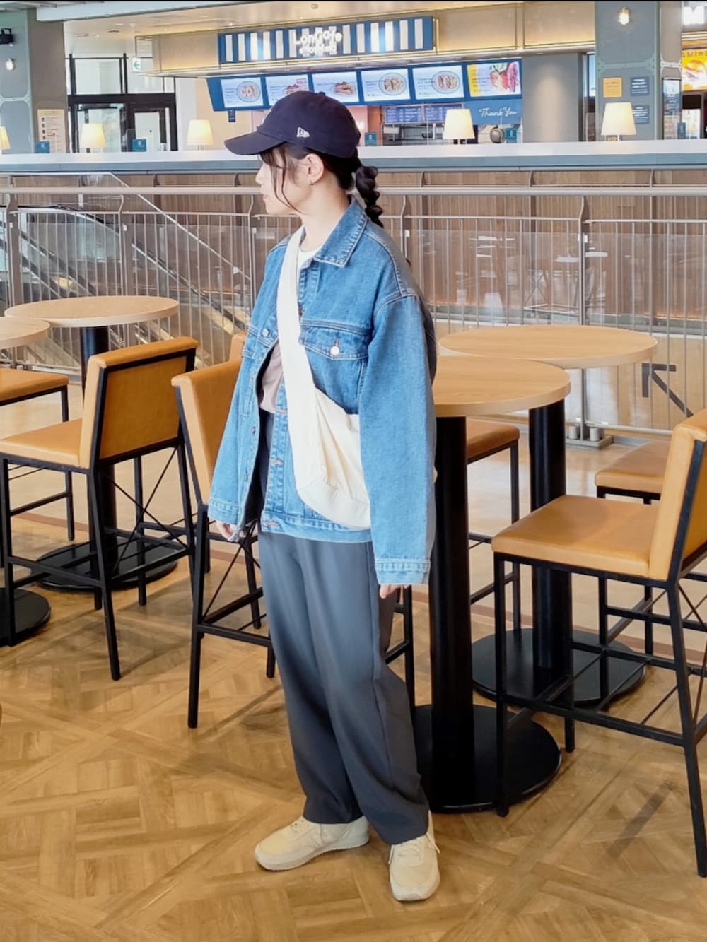 グレー系のスラックス、ブルー系のデニムジャケット、グリーン系のブルゾンを着用したレディースの春コーディネートの3枚目の写真