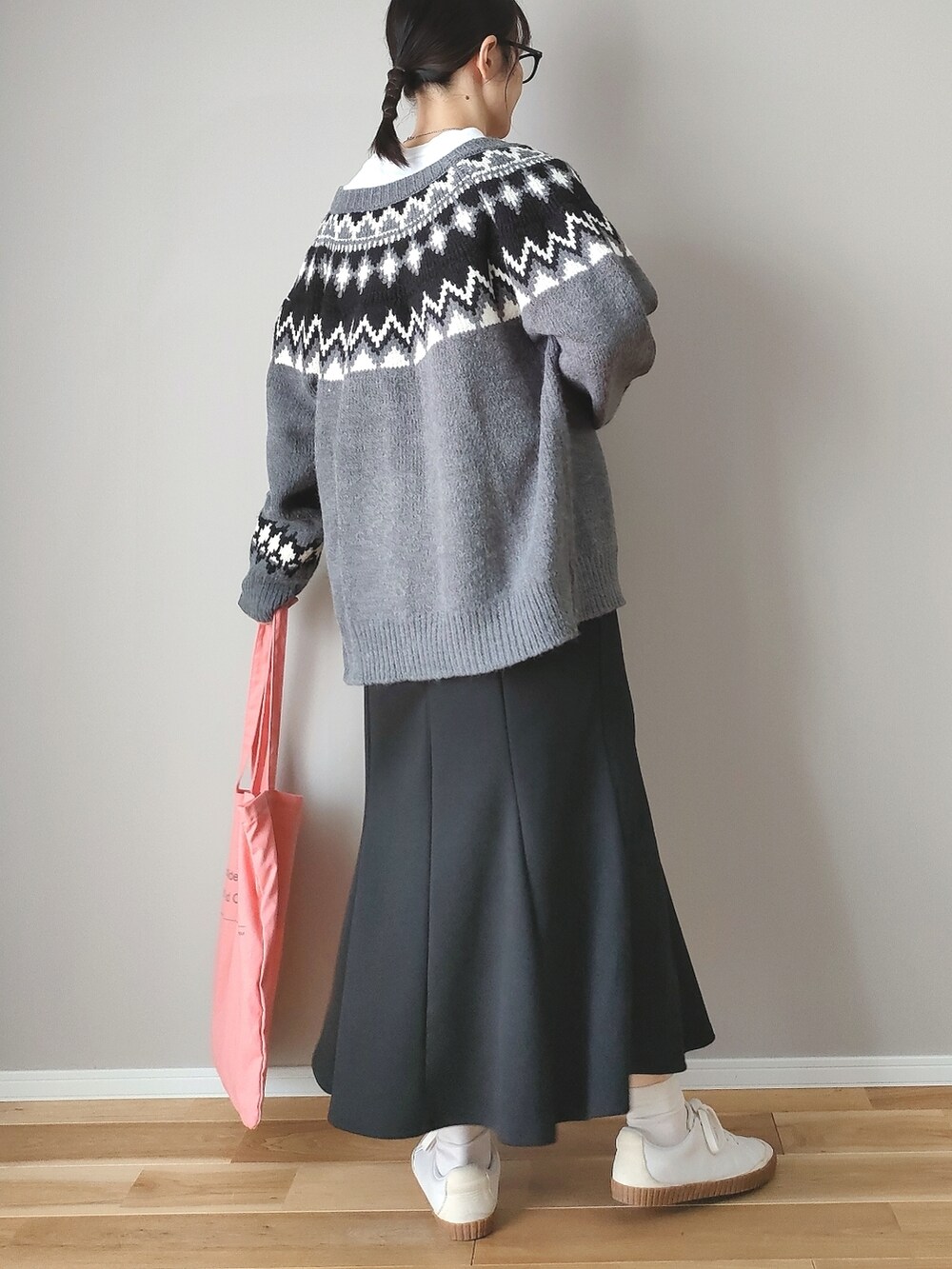 グレー系のニット/セーター、ブラック系のスカート、ピンク系のトートバッグを着用したレディースの秋コーディネートの3枚目の写真