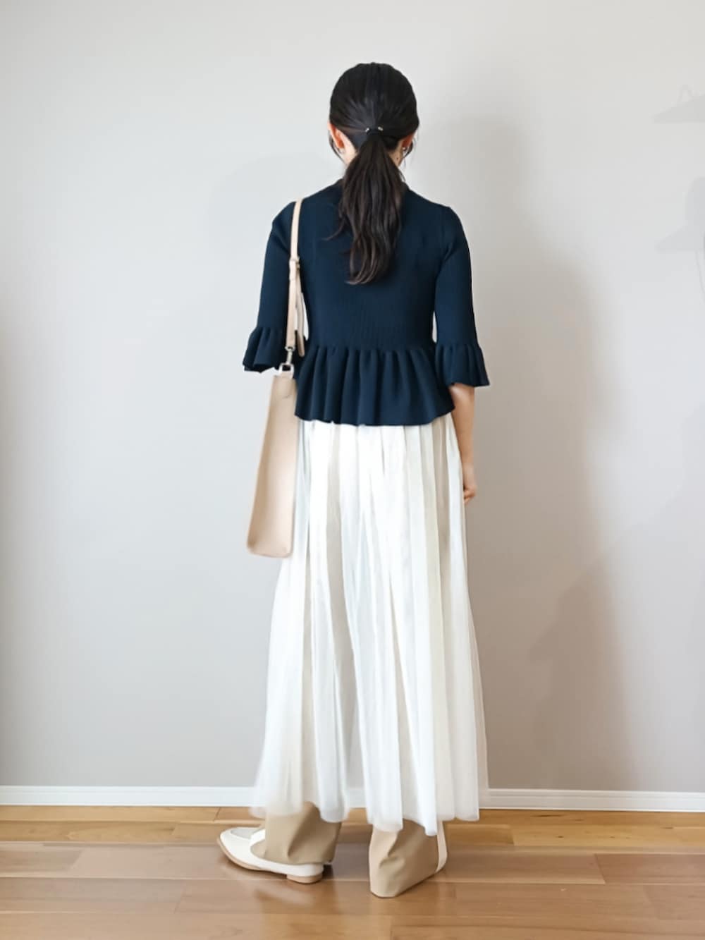 ブルー系のニット/セーター、ベージュ系のパンツ、ホワイト系のスカートを着用したレディースの春コーディネートの3枚目の写真