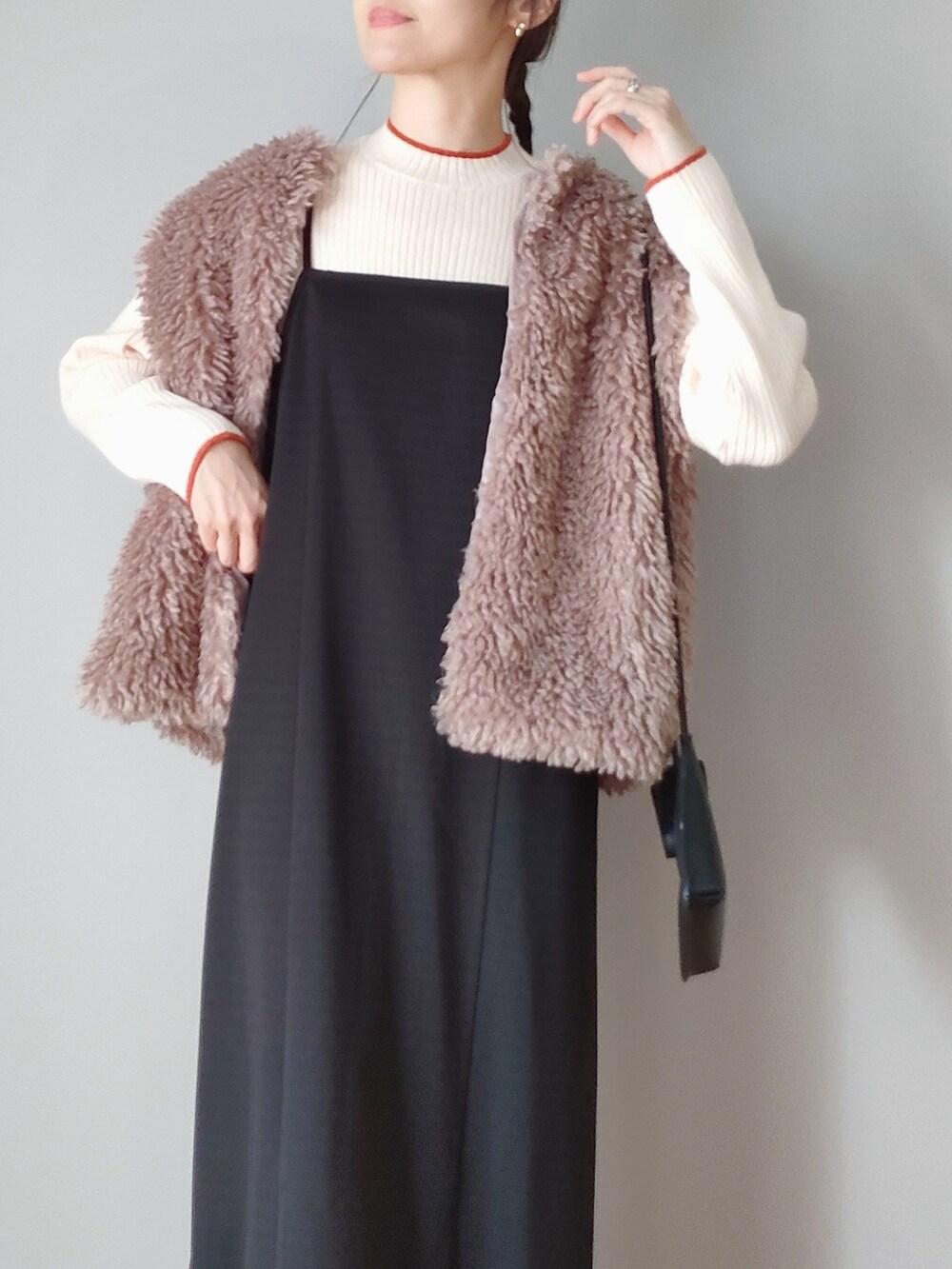 ベージュ系のベスト、ブラック系のワンピース、グリーン系のブーツを着用したレディースの秋コーディネートの2枚目の写真