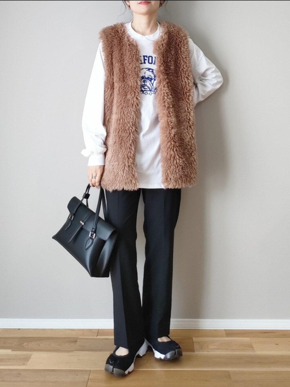 ホワイト系のTシャツ/カットソー、ブラウン系のベスト、ブラック系のハンドバッグを着用したレディースの秋コーディネートの3枚目の写真