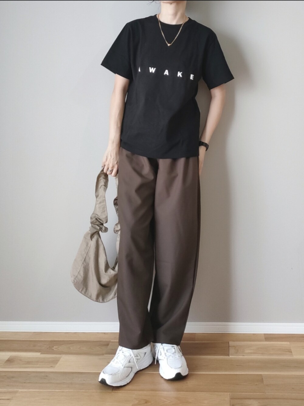 ブラウン系のスラックス、ブラック系のTシャツ/カットソー、ベージュ系のハンドバッグを着用したレディースの秋コーディネートの4枚目の写真