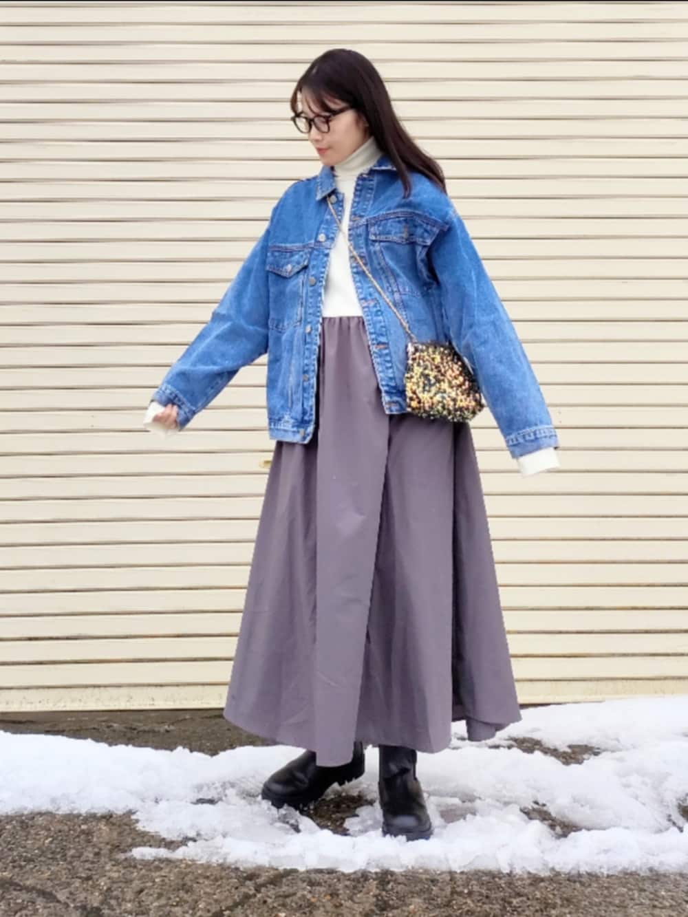 ブルー系のデニムジャケット、ホワイト系のワンピース、ゴールド系のハンドバッグを着用したレディースの冬コーディネートの3枚目の写真