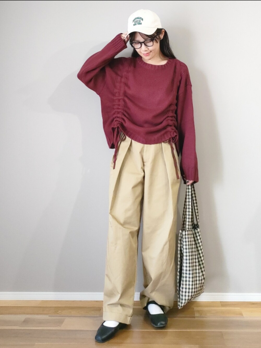 レッド系のニット/セーター、ベージュ系のチノパンツ、ベージュ系のトートバッグを着用したレディースの秋コーディネートの2枚目の写真