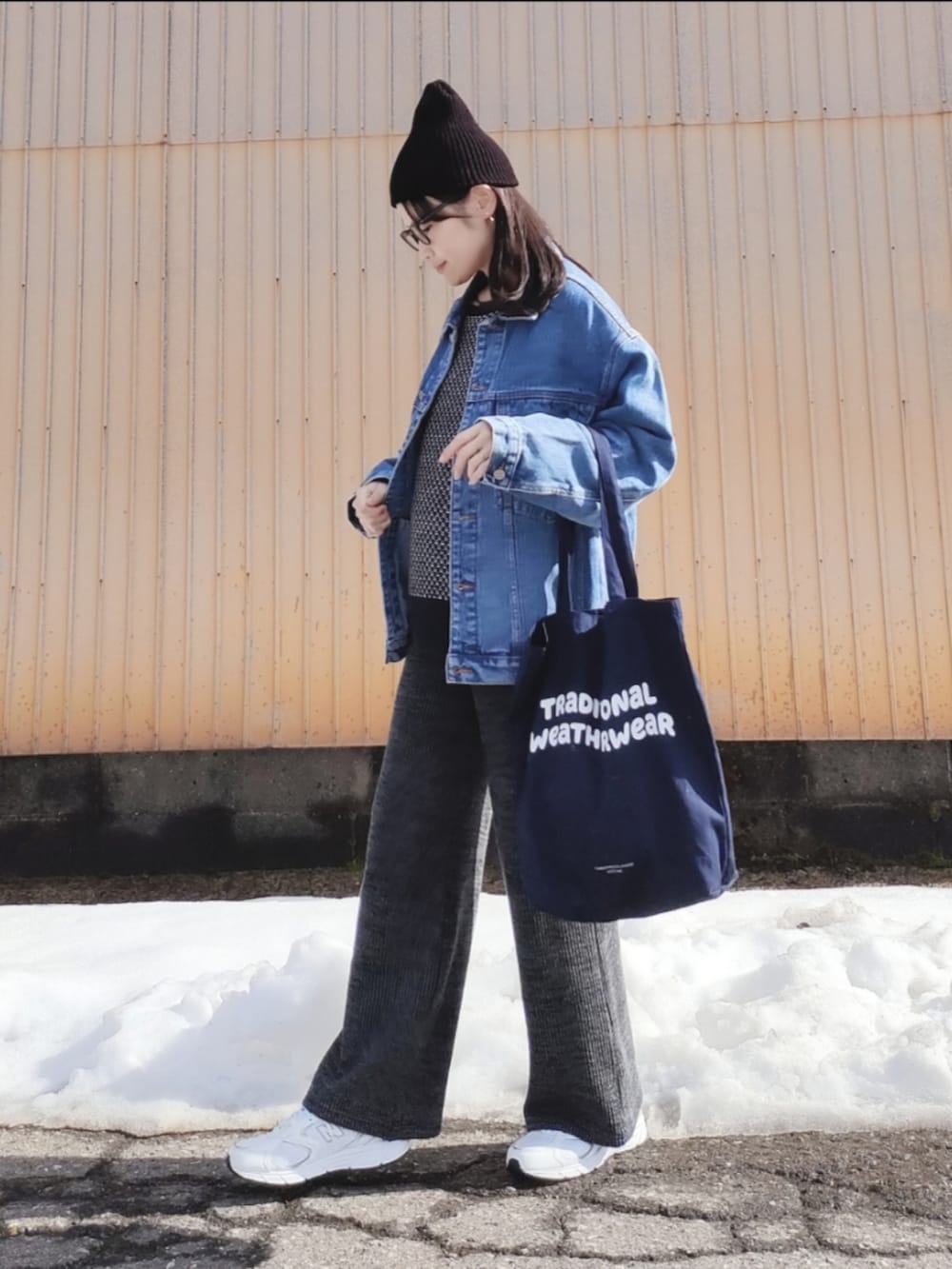 ブルー系のデニムジャケット、ブラック系のニット/セーター、ブルー系のトートバッグを着用したレディースの春コーディネートの3枚目の写真