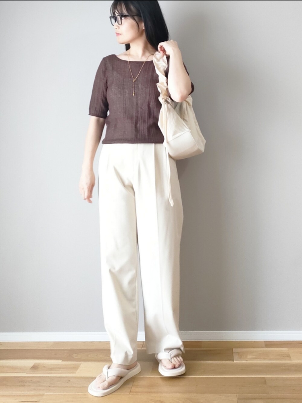 ブラウン系のニット/セーター、ホワイト系のハンドバッグ、ホワイト系のパンツを着用したレディースの夏コーディネートの3枚目の写真