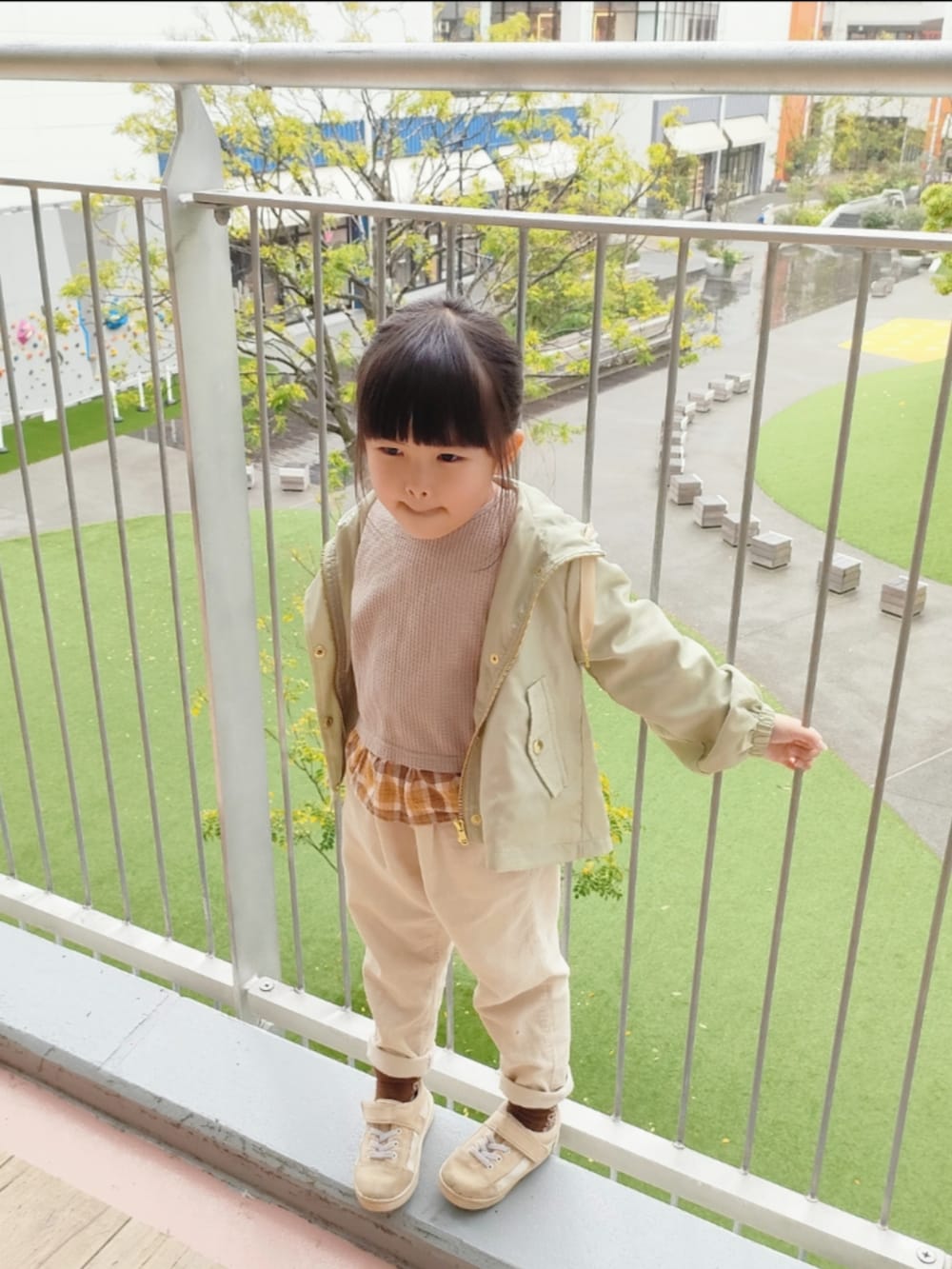 グレー系のスラックス、ブルー系のデニムジャケット、グリーン系のブルゾンを着用したレディースの春コーディネートの2枚目の写真