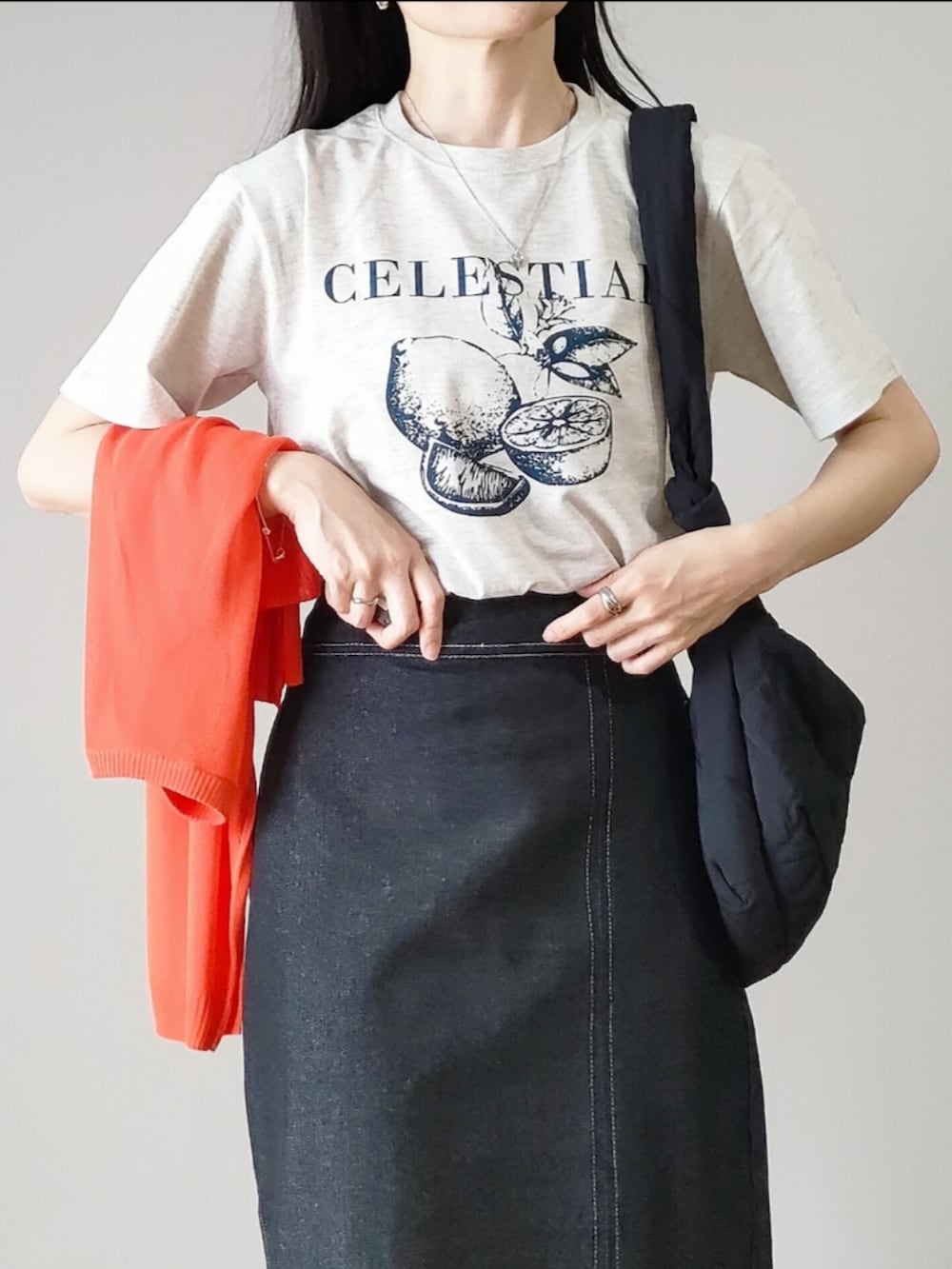 ベージュ系のTシャツ/カットソー、ブラック系のスカート、オレンジ系のカーディガン/ボレロを着用したレディースの春コーディネートの2枚目の写真