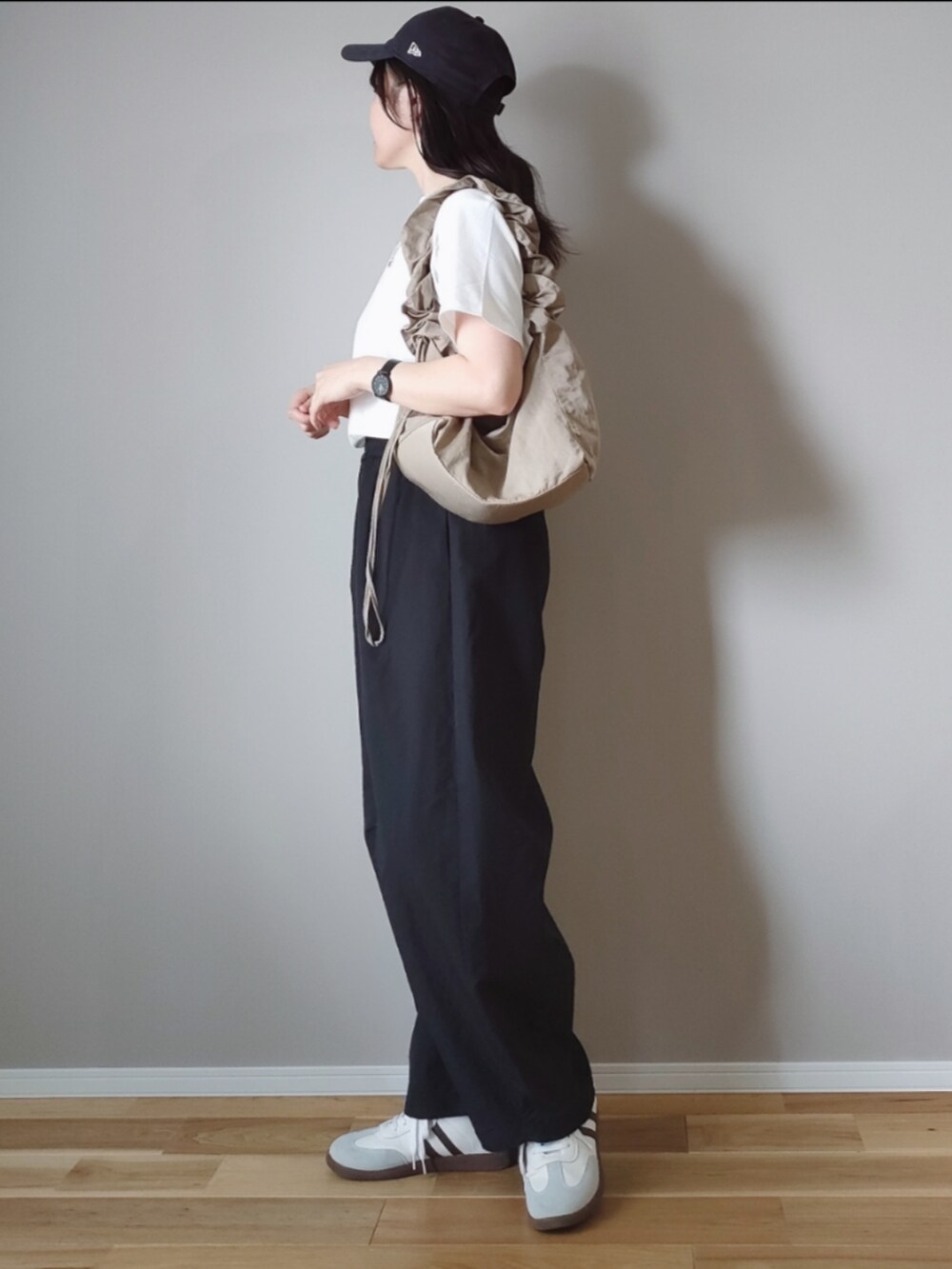 ブラック系のTシャツ/カットソー、ブラック系のカーゴパンツ、ベージュ系のハンドバッグを着用したレディースの春コーディネートの2枚目の写真