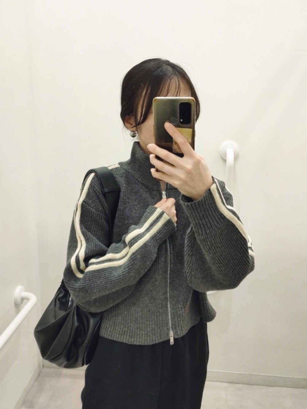 グレー系のニット/セーター、ブラック系のスウェットパンツ、ブラック系のショルダーバッグを着用したレディースの冬コーディネートの3枚目の写真