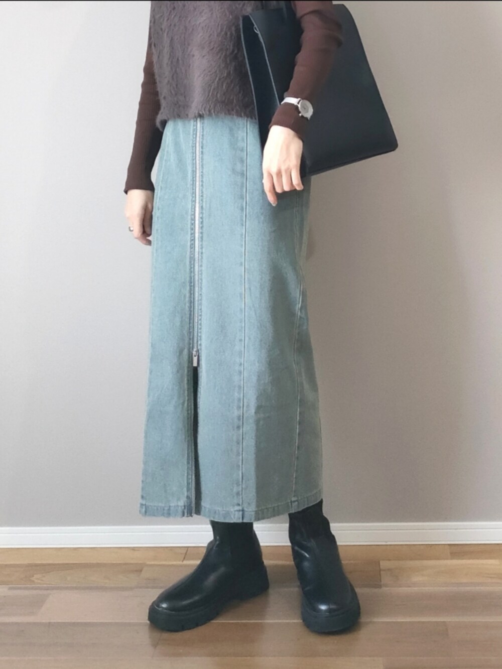 ブラック系のスカート、グレー系のベスト、ブラック系のブーツを着用したレディースの冬コーディネートの3枚目の写真