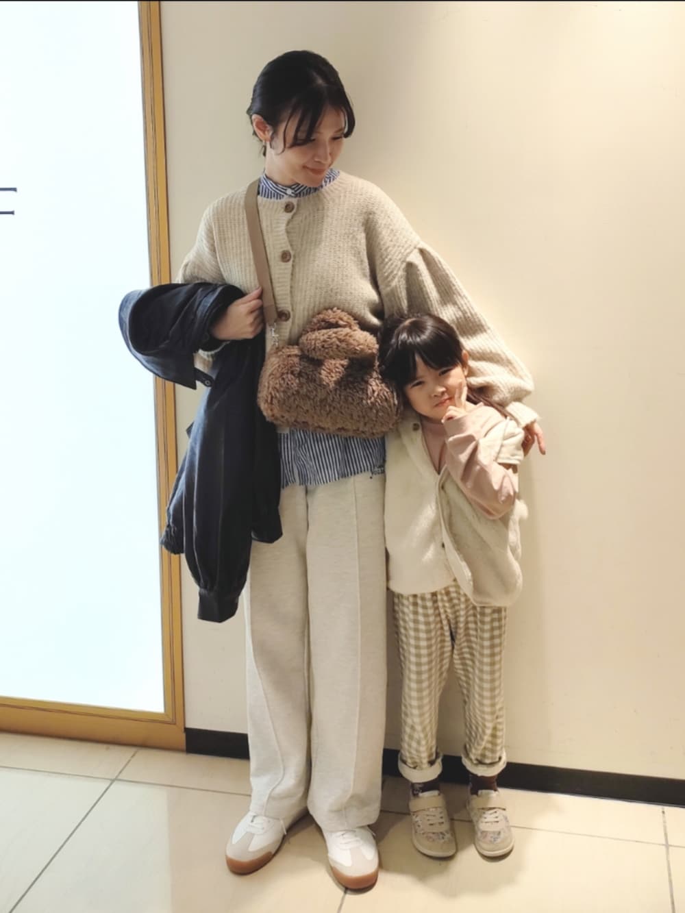 ベージュ系のスウェットパンツ、ブラック系のブルゾン、ホワイト系のカーディガン/ボレロを着用したレディースの秋コーディネートの2枚目の写真