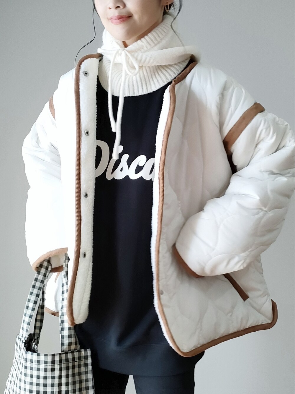 ホワイト系のブルゾン、ブラック系のデニムパンツ、ブラック系のスウェットを着用したレディースの秋コーディネートの2枚目の写真