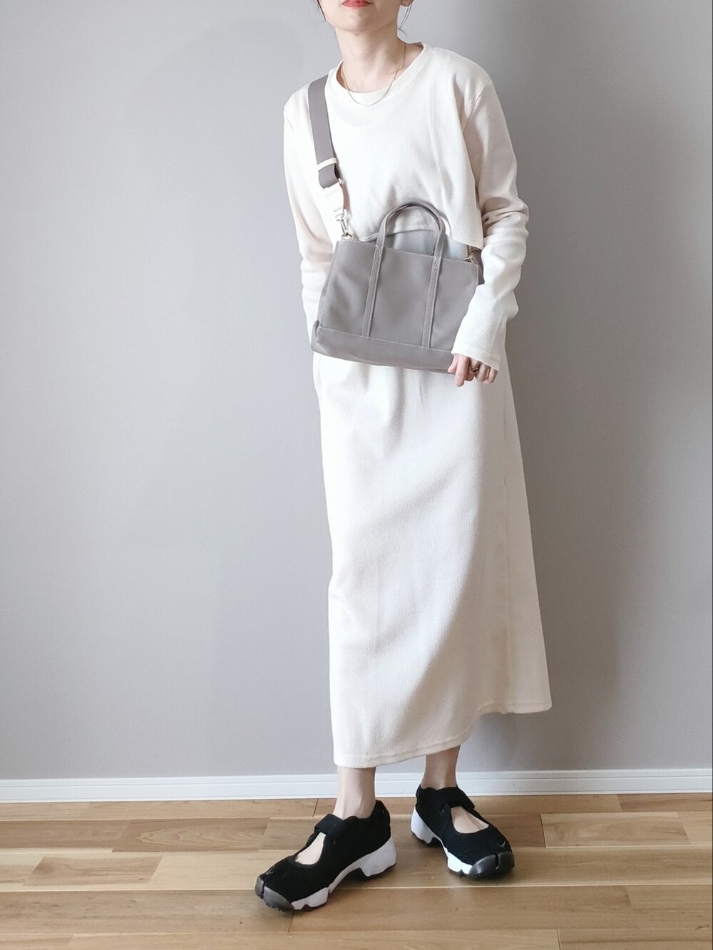 ホワイト系のワンピース、グレー系のハンドバッグ、ブラック系のスニーカーを着用したレディースの春コーディネートの3枚目の写真
