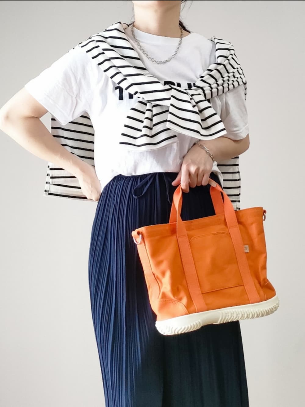 オレンジ系のトートバッグ、ブルー系のその他パンツ、ホワイト系のTシャツ/カットソーを着用したレディースの春コーディネートの2枚目の写真