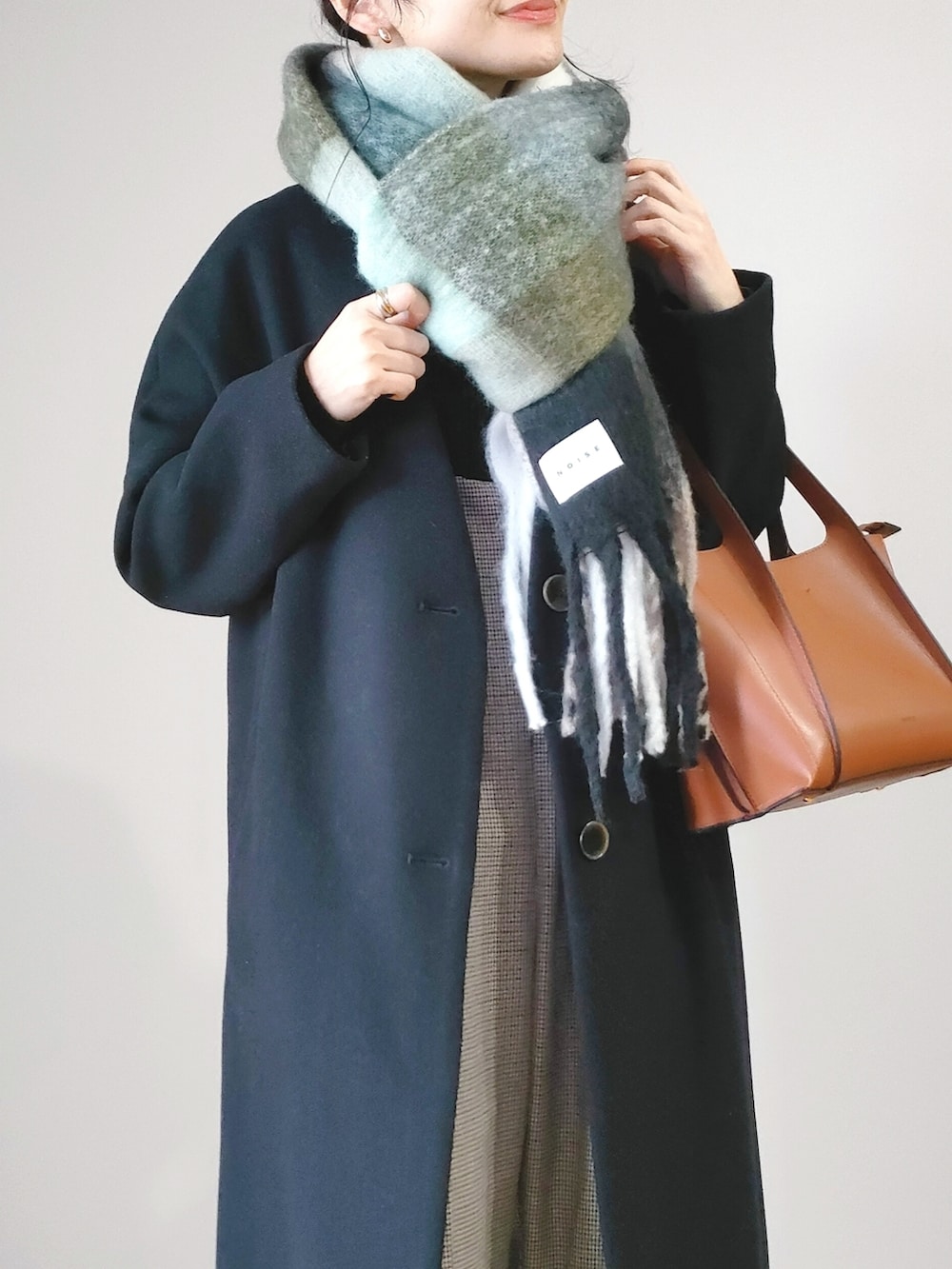 ブラウン系のショルダーバッグ、ブラック系のジャケット/アウター、ホワイト系のブーツを着用したレディースの冬コーディネートの2枚目の写真