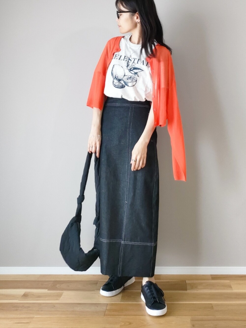 ベージュ系のTシャツ/カットソー、ブラック系のスカート、オレンジ系のカーディガン/ボレロを着用したレディースの春コーディネートの3枚目の写真