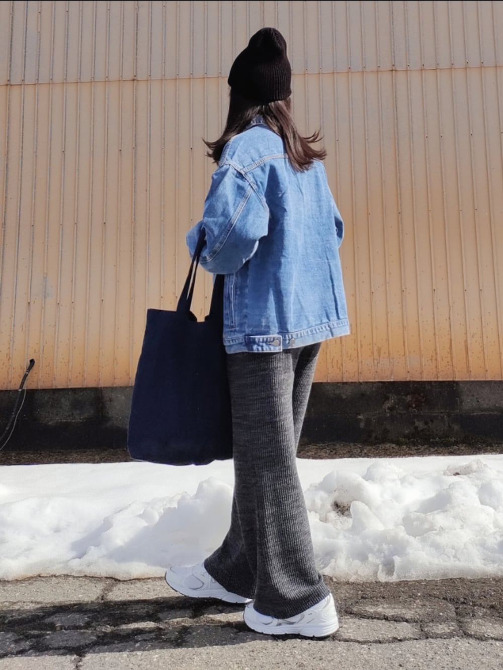 ブルー系のデニムジャケット、ブラック系のニット/セーター、ブルー系のトートバッグを着用したレディースの春コーディネートの4枚目の写真