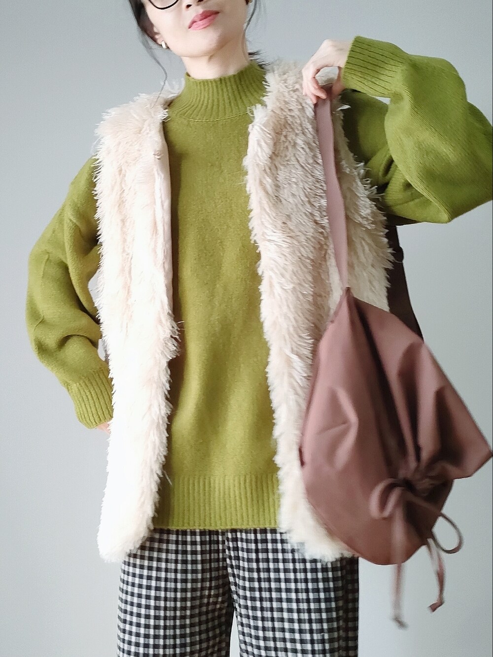 グリーン系のニット/セーター、ホワイト系のベスト、ブラウン系のショルダーバッグを着用したレディースの秋コーディネートの2枚目の写真