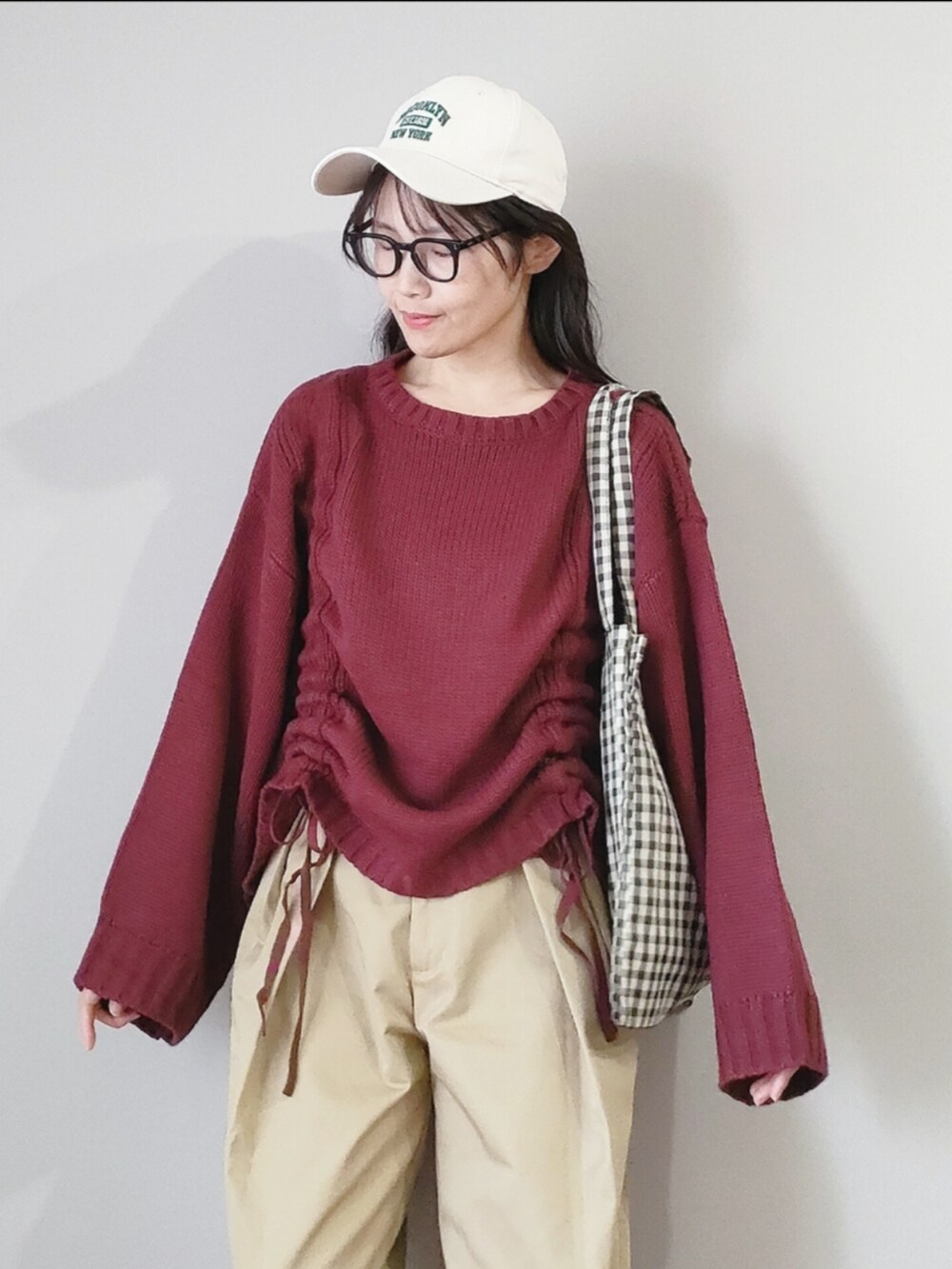 レッド系のニット/セーター、ベージュ系のチノパンツ、ベージュ系のトートバッグを着用したレディースの秋コーディネートの3枚目の写真