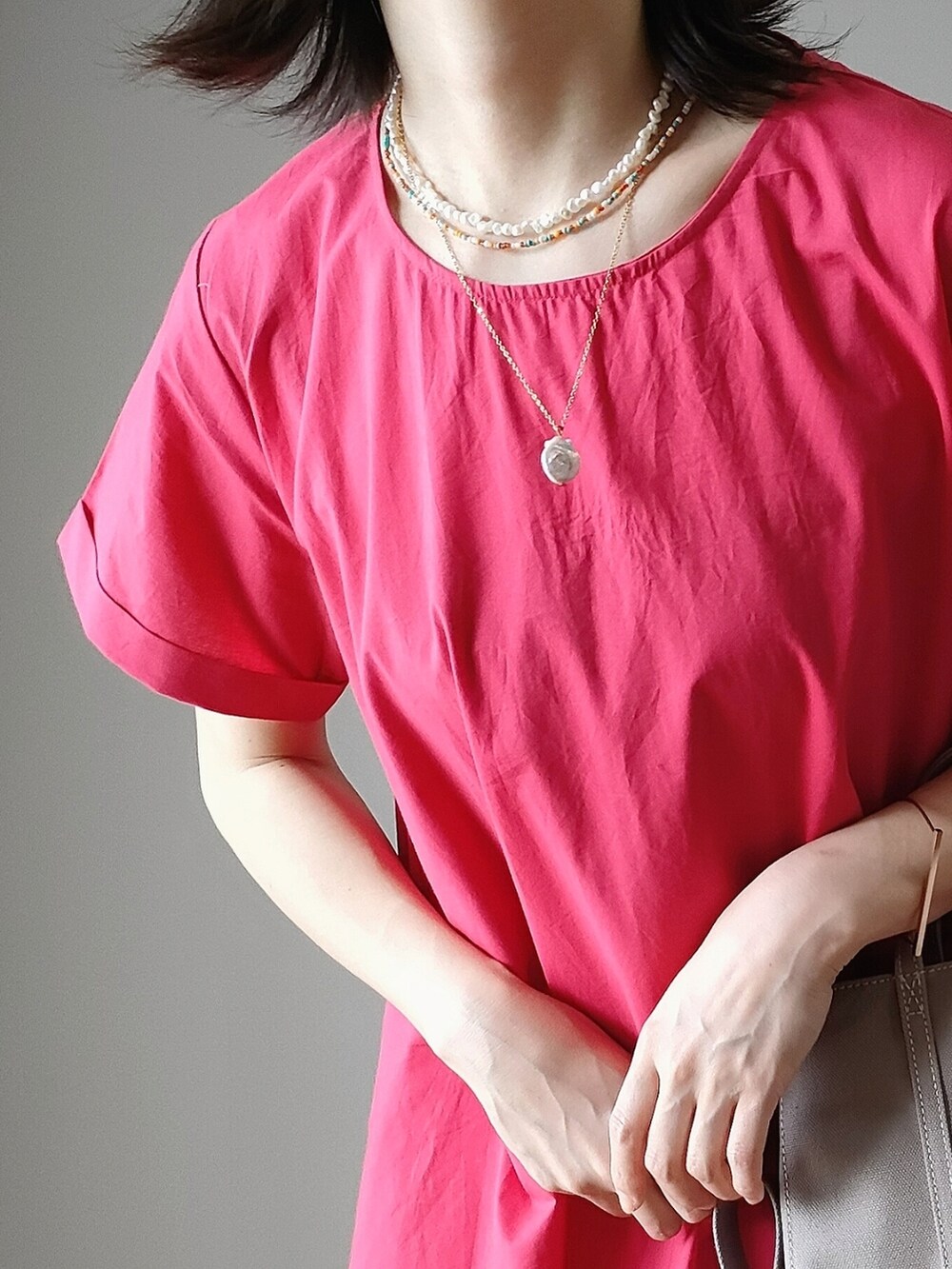 レッド系のワンピース、グレー系のハンドバッグ、ホワイト系のサンダルを着用したレディースの夏コーディネートの3枚目の写真