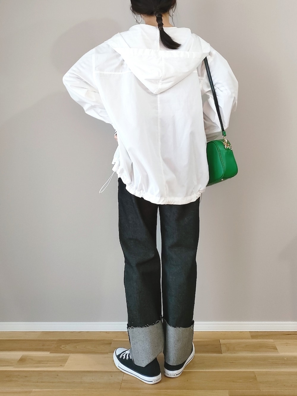グリーン系のショルダーバッグ、ホワイト系のマウンテンパーカー、ブラック系のデニムパンツを着用したレディースの春コーディネートの4枚目の写真