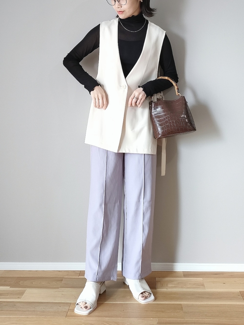 ブラック系のTシャツ/カットソー、ホワイト系のベスト、ホワイト系のサンダルを着用したレディースの春コーディネートの2枚目の写真