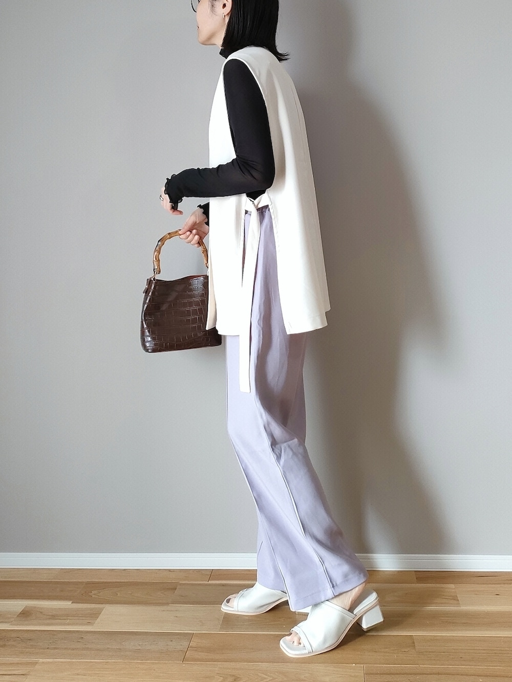 ブラック系のTシャツ/カットソー、ホワイト系のベスト、ホワイト系のサンダルを着用したレディースの春コーディネートの4枚目の写真