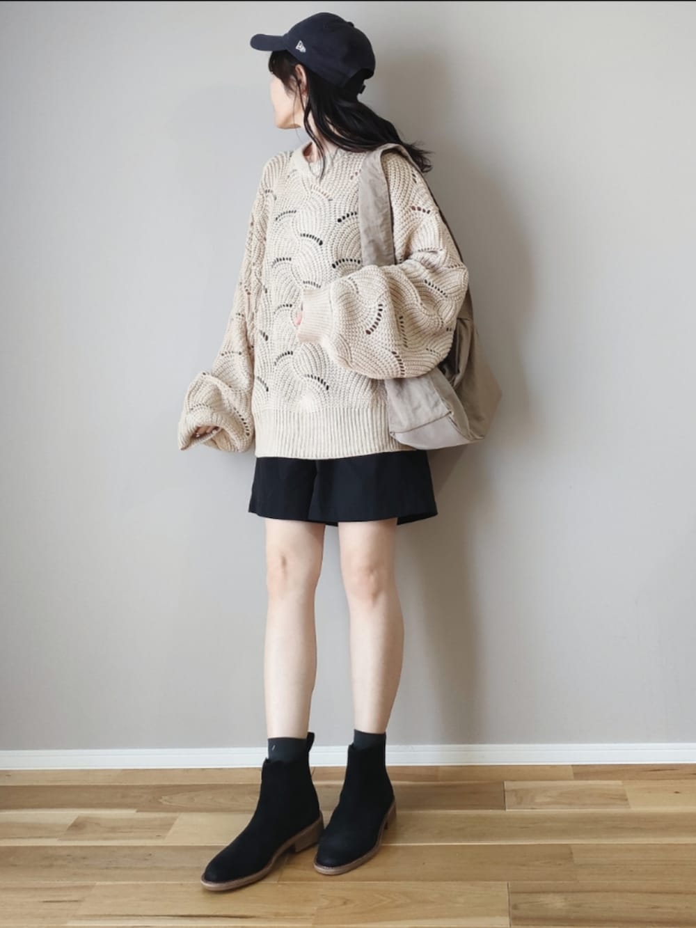 ホワイト系のニット/セーター、ベージュ系のハンドバッグ、ブラック系のブーツを着用したレディースの秋コーディネートの3枚目の写真